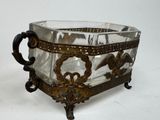 a glass bowl with a metal handle on a stand
