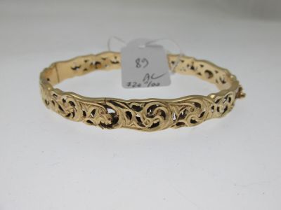 un bracelet en or avec un motif en filigrane sur fond blanc