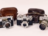 four cameras are lined up in a row on a white surface