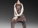 a close up of a statue of a person sitting on a chair