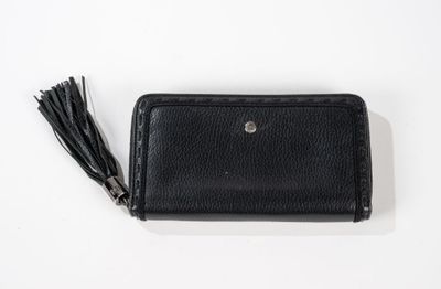 un portefeuille en cuir noir orné d'un pompon sur un fond blanc