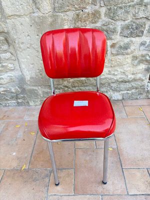 une chaise rouge posée devant un mur de pierre