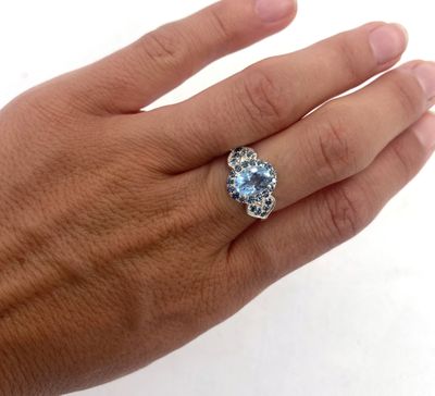 Quelqu'un tient une bague sertie d'une pierre bleue.