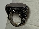 a ring with a black stone in it on a white pillow