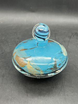 un petit bocal en verre avec un couvercle bleu posé sur une table
