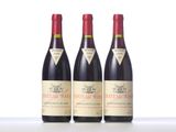 three bottles of red wine are lined up on a table
