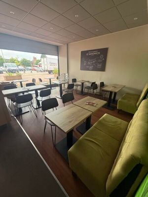 tables and chairs in a room with a large window and a green couch