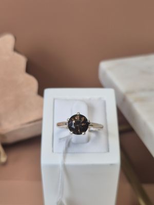 une bague en diamant noir dans une boîte blanche posée sur une table