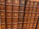 many old books stacked on top of each other on a shelf