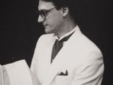 black and white photograph of a man in a suit and tie holding a book