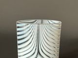 white and black swirly glass vase on a dark surface