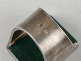a close up of a silver ring with a green stone in it