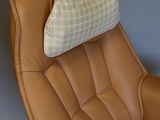 brown leather chair with a plaid pillow on the back of it