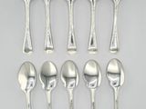 six silver spoons and two silver spoons on a white surface