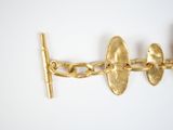 a close up of a gold bracelet with a bar on it