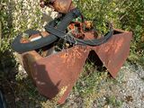 un objet métallique rouillé posé dans l'herbe à côté d'une poubelle