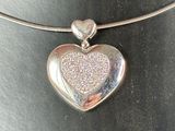 silver heart shaped pendant on a silver necklace on a black surface