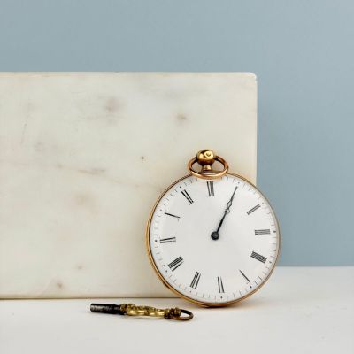 un bloc de marbre blanc sur lequel repose une montre de poche en or