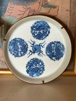a blue and white plate sitting on a shelf next to a picture