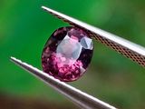 un gros plan d'un diamant rose tenu par une paire de pinces