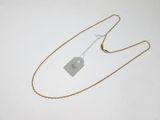 une chaîne en or à laquelle est accrochée une médaille, posée sur une surface blanche