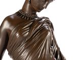 bronze statue of a woman in a dress with a necklace on her neck
