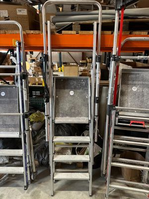 several metal ladders are stacked on top of each other in a warehouse