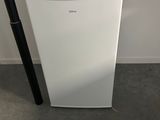 a small white refrigerator with a remote control on top of it