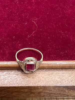 Gros plan sur une bague en or ornée d'une pierre rouge