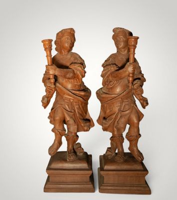 pair of carved wood figures of a man and a woman holding a torch