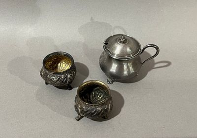 une théière en argent et deux tasses en argent posées sur une table
