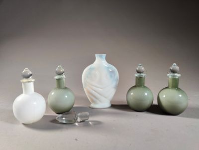 five glass bottles and a glass vase on a table