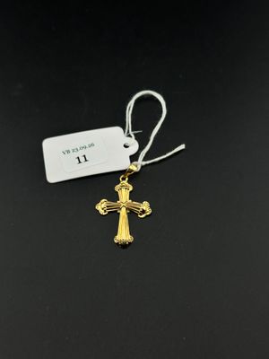 un pendentif en forme de croix en or avec une étiquette, sur fond noir