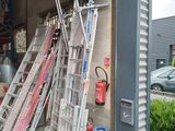 many ladders leaning up against the wall of a garage