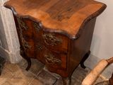 a small chest of drawers next to a chair in a room