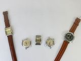 two watches and a wrist watch are sitting on a white surface