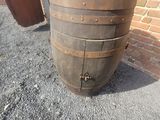 a wooden barrel sitting on the ground next to a brick wall