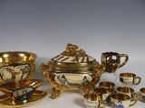 un service à thé doré, avec des tasses et des soucoupes, posé sur une table blanche