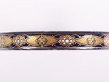 un gros plan d'un bracelet doré et noir sur fond blanc