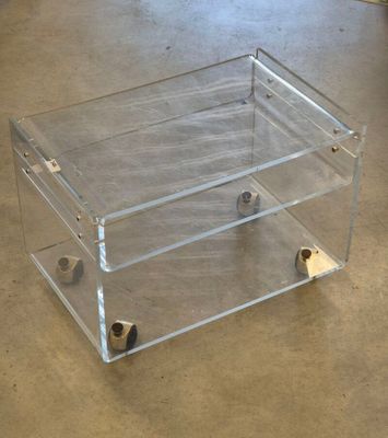 une boîte transparente munie de roulettes, posée au sol