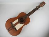Une vieille guitare en bois est posée sur une surface blanche
