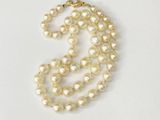 a close up of a pearl necklace on a white surface