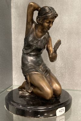 une statue en bronze représentant une femme assise sur un socle