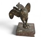 statue d'un oiseau posée sur un socle en marbre, sur fond blanc