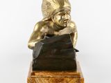 bronze statue of a man with a headdress resting on a rock