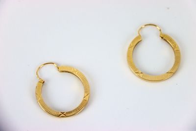 two pairs of gold hoop earrings on a white surface