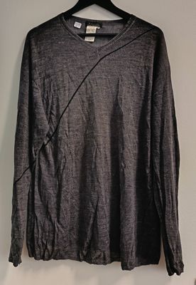 grey long - sleeved shirt hanging on a hanger on a wall