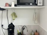a microwave on a shelf above a sink in a kitchen