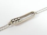 a close up of a silver necklace with a chain on a white surface