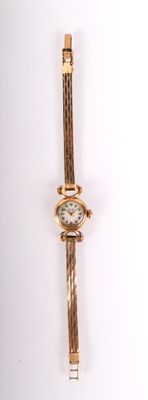une montre-bracelet en or avec un cadran blanc sur une surface blanche